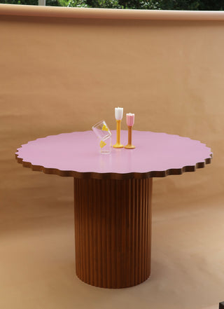 Round table with a scalloped pink top and ribbed brown base on a beige background