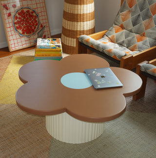 Flower-shaped coffee table with a laptop on top in a room setting.