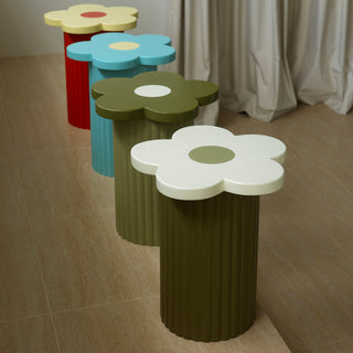 Colorful flower-shaped stools arranged in a row against a neutral wall.