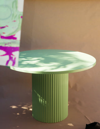 Green round table with ribbed cylindrical base on a neutral background